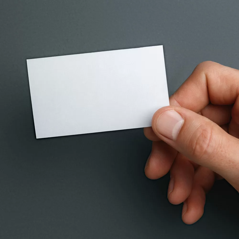 Male hand holding a blank business card on grey background for text or design