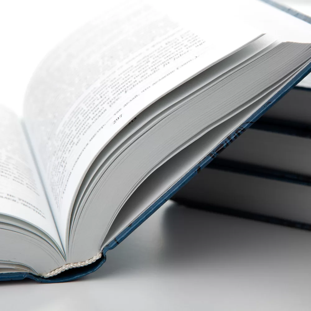 book printed with uncoated smooth paper with a stack of books on a gray table