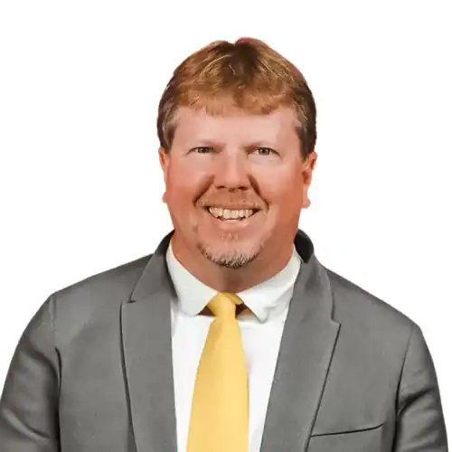 Professional headshot of Mike Williams wearing a gray suit and yellow tie against a white background.