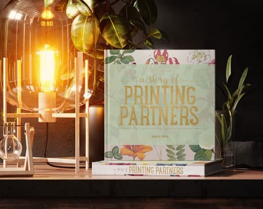 Square book cover featuring floral design and foil stamp text that reads 'a story of PRINTING PARTNERS'.