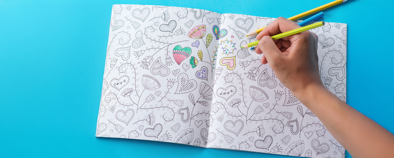 Female hands coloring anti stresss color book with hearts and flowers pattern. Art therapy concept. Healthy lifestyle, leisure. Artwork for adults.