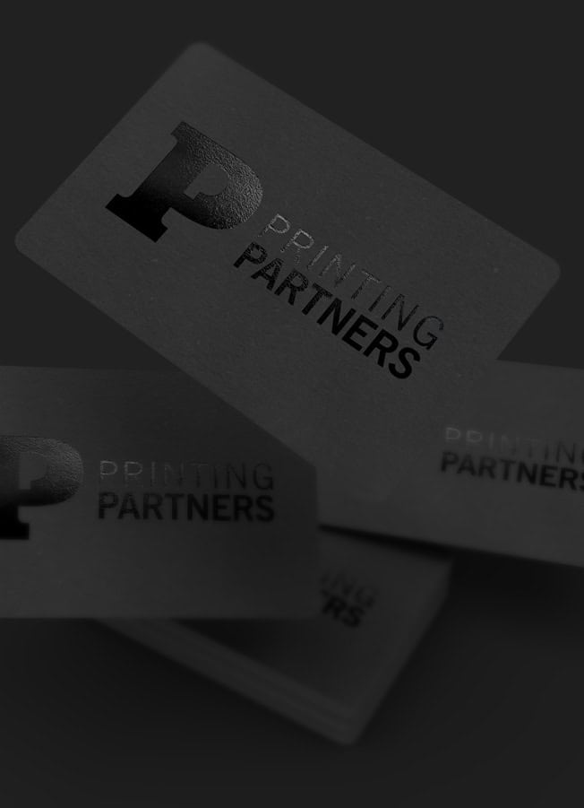 Black business cards with embossed logo and text from Printing Partners.