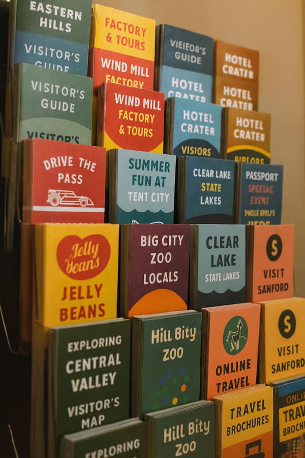 A rack card display case featuring various travel-related brochures and guides.