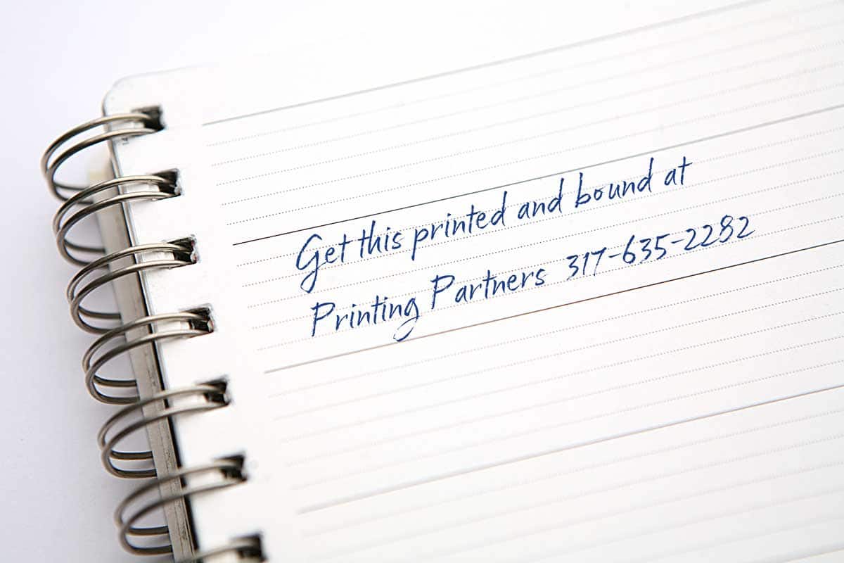 Close-up of a Printing Partners Wire-O bound notebook showing the double loop metal wire threaded through punched holes along the spine.