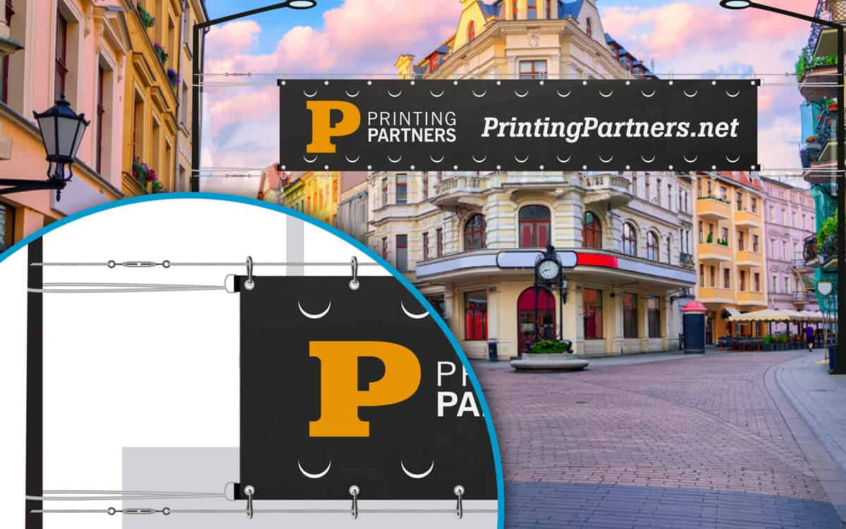 A large vinyl banner mounted over a street with mounting hardware detail