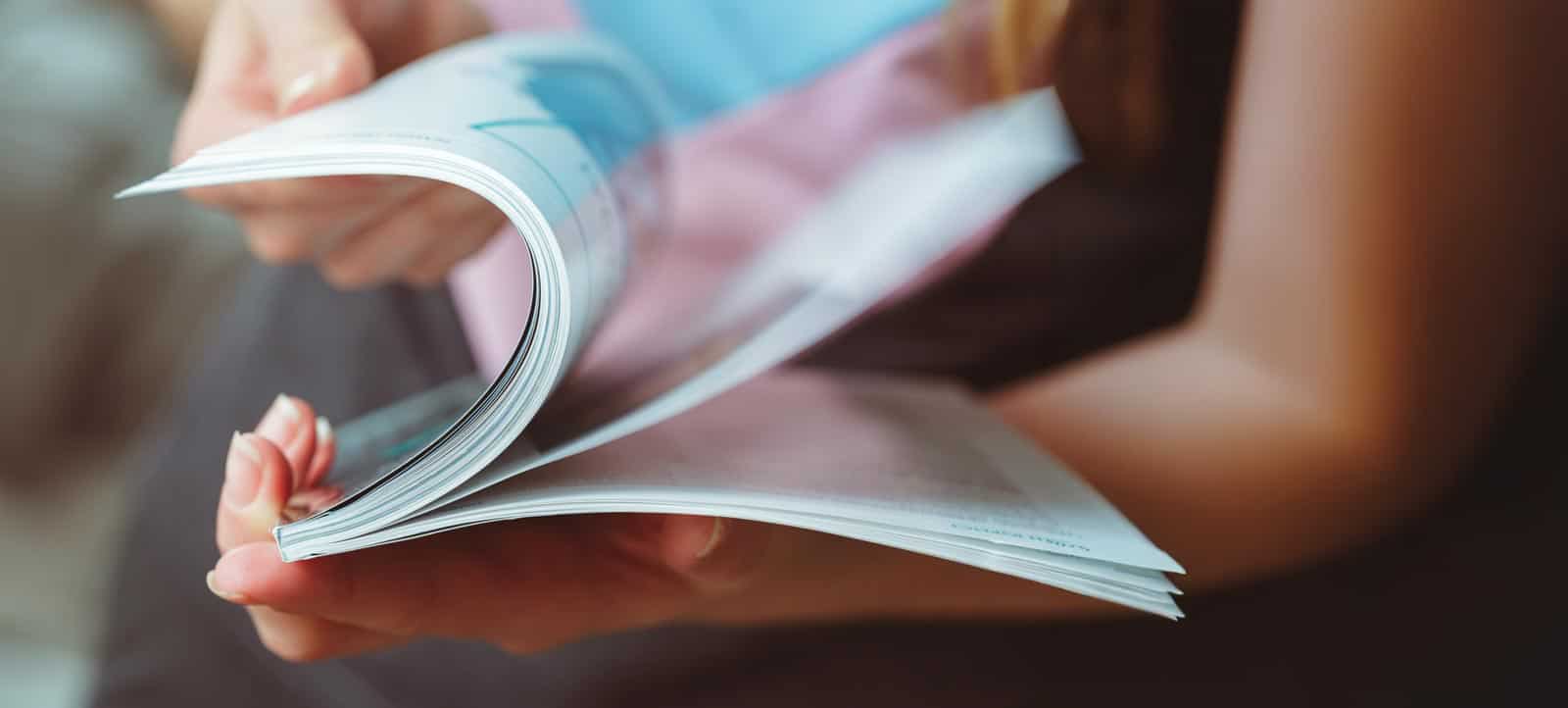 A reader turning the pages of a printed magazine