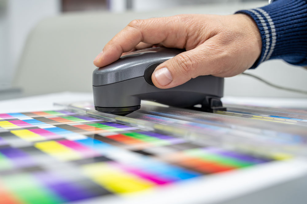 A Printing Partners technician checking color calibration on a press sheet