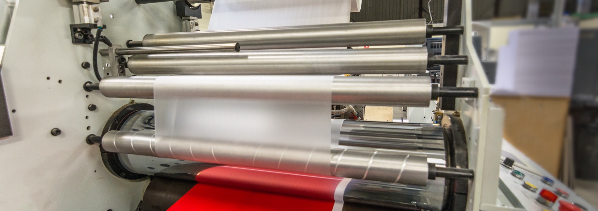 Laminating film running through rollers over a printed sheet