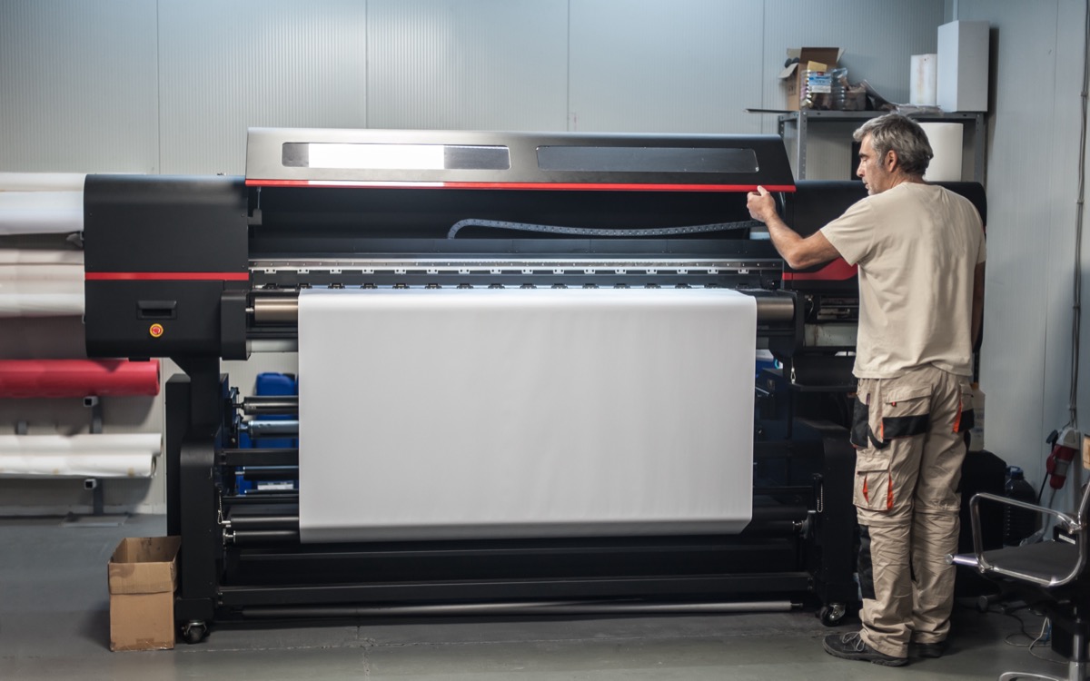 Operator loading roll media into a large format printer