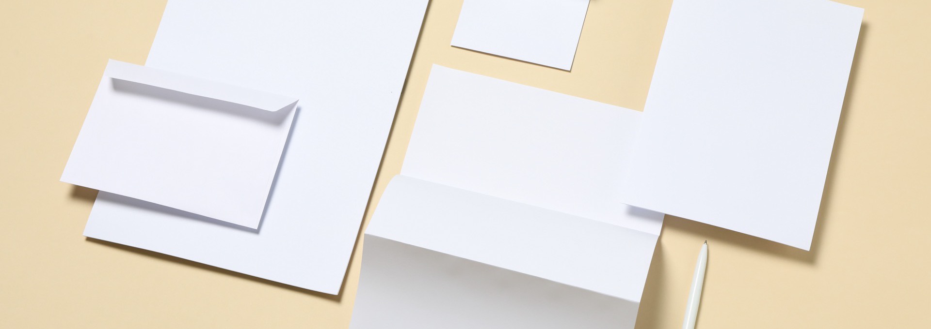 Uncoated letterhead, envelopes and business cards laid out on a warm beige surface