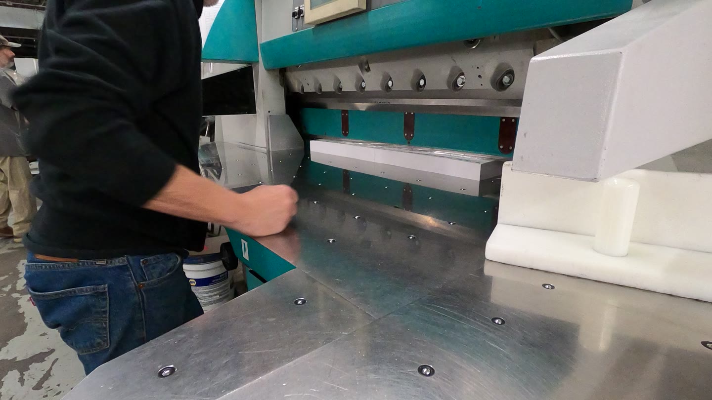 Operator aligning a paper stack at the cutting machine