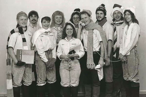A group of individuals wearing winter clothing and accessories, posing together in a studio setting.